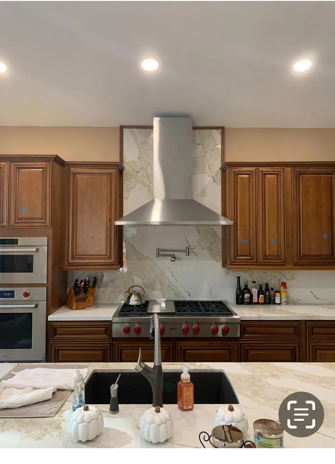 Kitchen with a full-height marble backsplash behind a stainless range hood